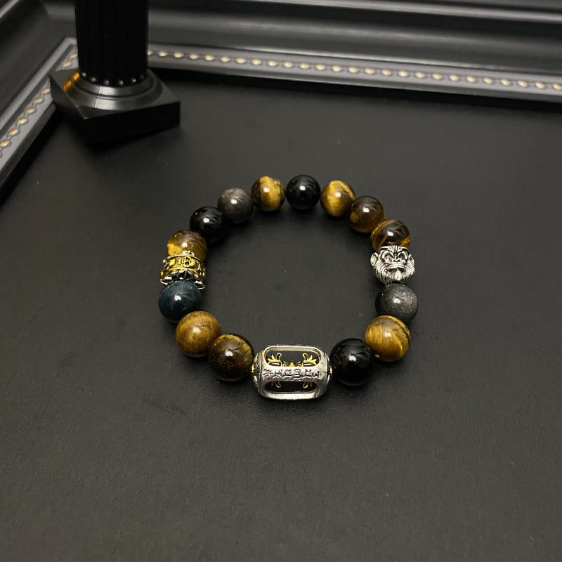 Tiger Eye Bracelet – Flat lay of tiger eye beads with gold and silver charms on black surface, men's wealth bracelet