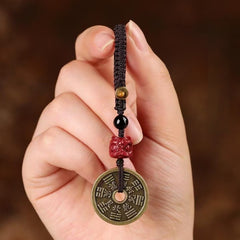 Hand holding Cinnabar Bagua Mountain Ghost keychain with red cinnabar bead and trigram coin