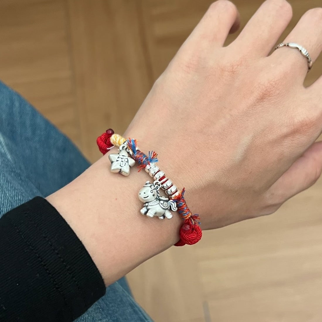 Horse Red String Bracelet – Worn on wrist with silver horse and star charms, black sleeve, zodiac jewelry