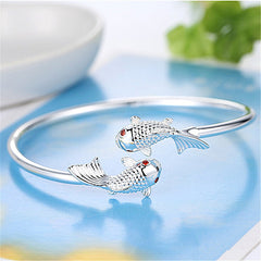 Double Fish Cuff – silver open cuff with twin koi fish on blue surface with green leaves