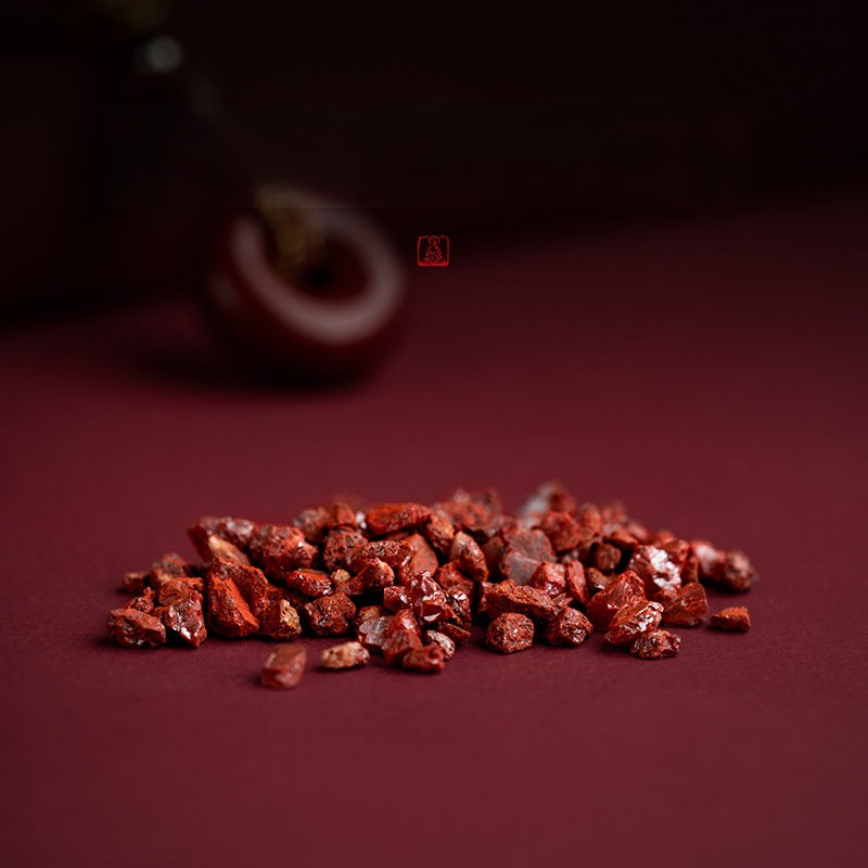 Raw natural cinnabar stone crystals material scattered on red surface