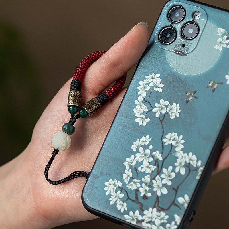 Lotus Bodhi Lanyard – Hand gripping phone with red woven lanyard and blue floral case, everyday use protection accessory