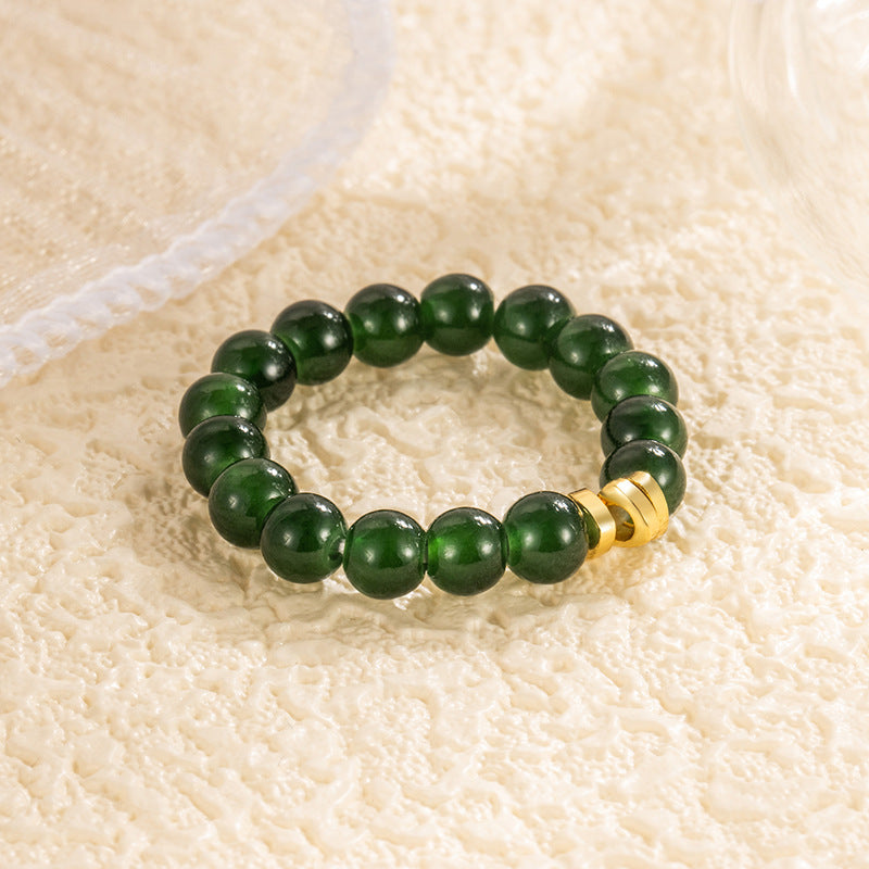 Jade Bead Ring – rich dark green jade beads glowing on cream texture, gold barrel connector, close-up gemstone jewelry detail