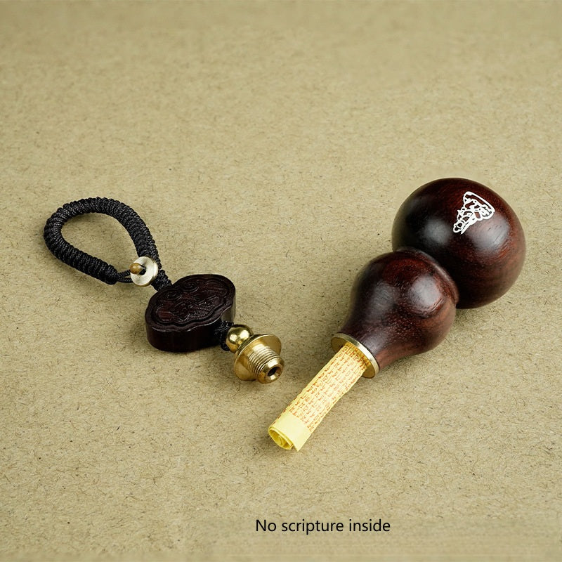 Red sandalwood gourd keychain opened revealing hollow interior with scripture scroll inside