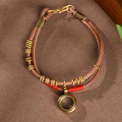 Gau Box Bracelet – overhead flat lay of double leather with gold coils and red thread accents, boho style