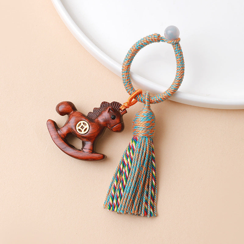 Rainbow Wooden Horse Keychain – close-up of reddish-brown horse with coin emblem and yarn tassel