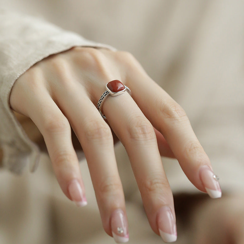 Red Agate Openwork Ring – elegant hand pose with French manicure on soft beige background, red agate ring