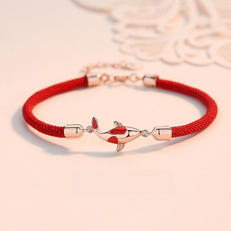 Koi Bracelet – red braided cord with rose gold koi charm on soft pink background