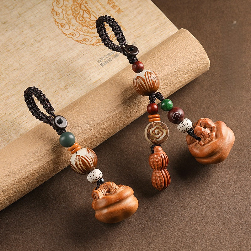Two peach wood keychains side by side, one with peanut charm and one without