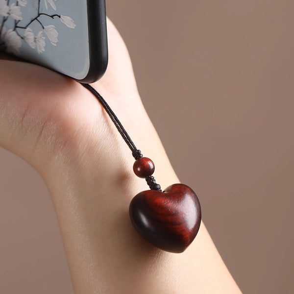 Rosewood Heart Keychain – heart charm attached to floral phone case, hand-held lifestyle shot