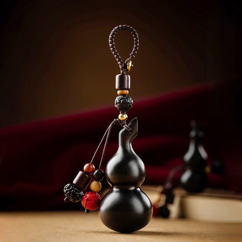 Sandalwood Gourd Keychain – upright dark gourd with lotus bead, blurred duplicate in background