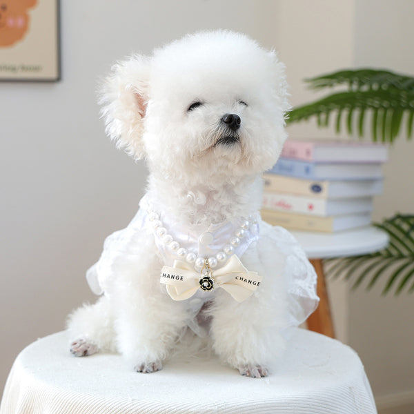 Luxury Crystal Pet Necklace – Bichon Frise wearing pearl collar with black bow and camellia charm, white ruffled dress