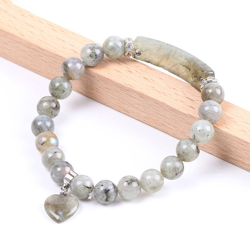 Natural Multi-Stone Love Heart Healing Bracelet - Labradorite bracelet on wood display with gray-green beads, blue-gold iridescent flash, curved bar, and heart pendant