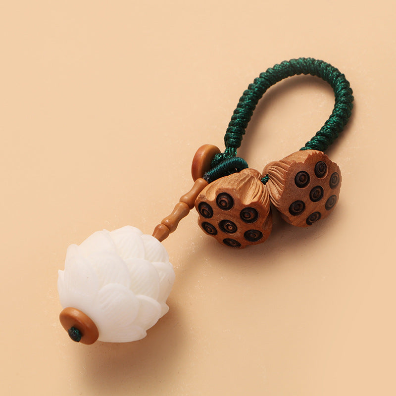 Bodhi Seed Peach Wood Lotus Keychain – Close-up of paired wooden lotus seed pods with carved dark chambers on green lanyard