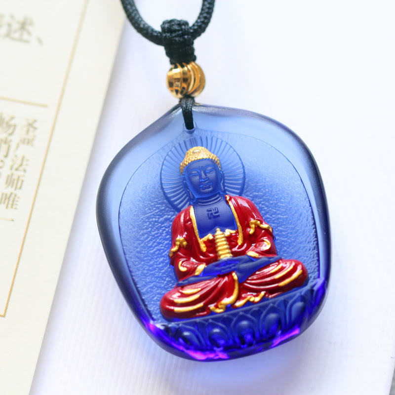 Liuli Crystal Medicine Buddha Pendant – blue liuli Buddha holding pagoda on book with black cord, front