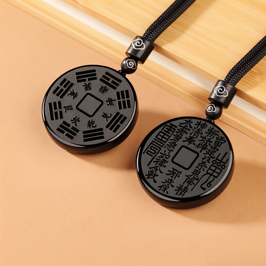 Obsidian Bagua Pendant – two black carved pendants on peach background, trigram and calligraphy sides