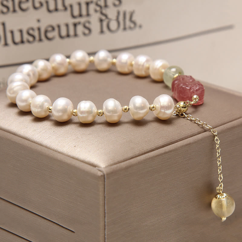 Pearl Strawberry Quartz PiXiu Bracelet – Angled view of pearls with pink PiXiu charm on brown box