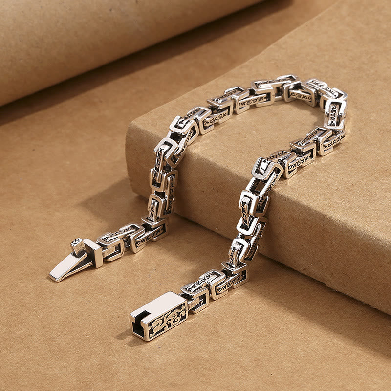 Dragon Om Mani Padme Hum Copper Bracelet - antiqued silver-tone copper box chain bracelet with engraved Tibetan Buddhist mantra links and gold dragon motif clasp, displayed on kraft paper platform