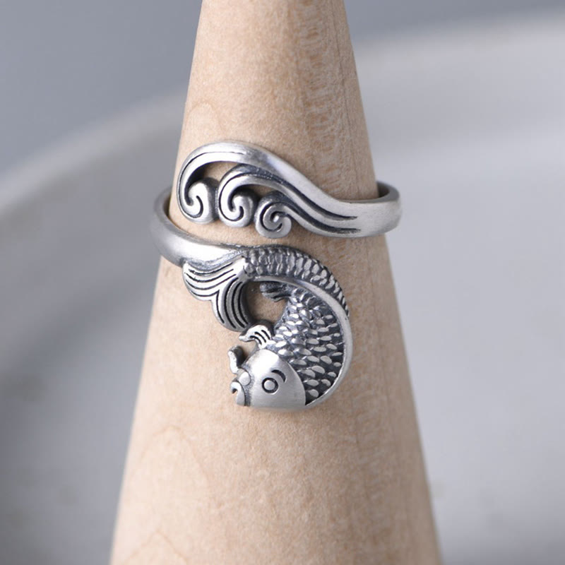 925 Sterling Silver Koi Ring – worn on middle finger, hand resting on wooden surface, water ripple koi silver ring