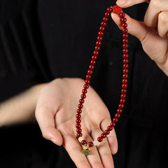 Cinnabar Lotus Bracelet – held in hands on dark background showing enamel lotus charm