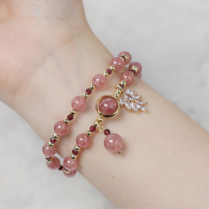 Strawberry quartz bracelet on wrist with two-layer wrap design featuring pink beads gold tone bezel setting clear crystal leaf spray and pink teardrop dangle