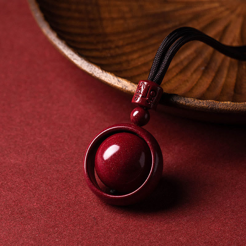 Cinnabar PiXiu Necklace – Black cord pendant by wooden bowl on red surface, prosperity blessing jewelry