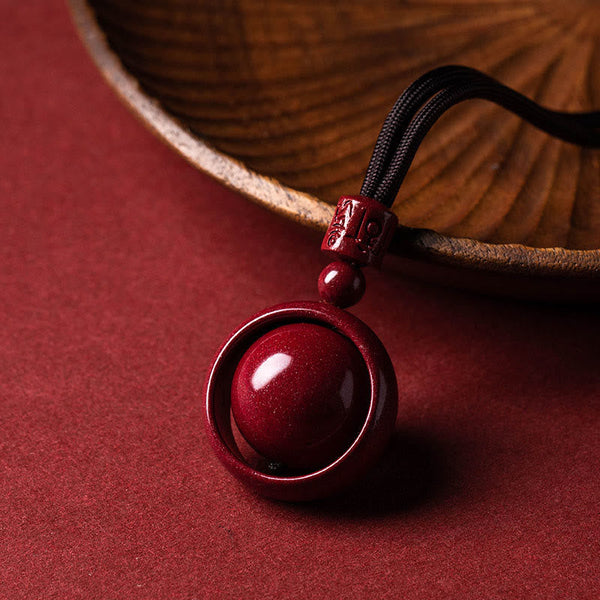 Cinnabar PiXiu Necklace – Black cord pendant by wooden bowl on red surface, prosperity blessing jewelry