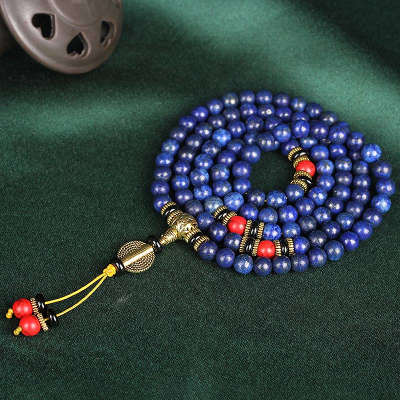 Lapis Lazuli Red Turquoise Tibetan Mala Bracelet coiled spiral on green velvet with ceramic prop, 108 lapis beads with gold flecks, red coral accents, gold guru bead, yellow cord tassel, studio product shot