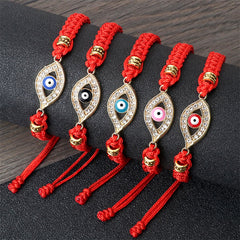 Red cord evil eye bracelet with gold crystal charm on white marble with wood and lace