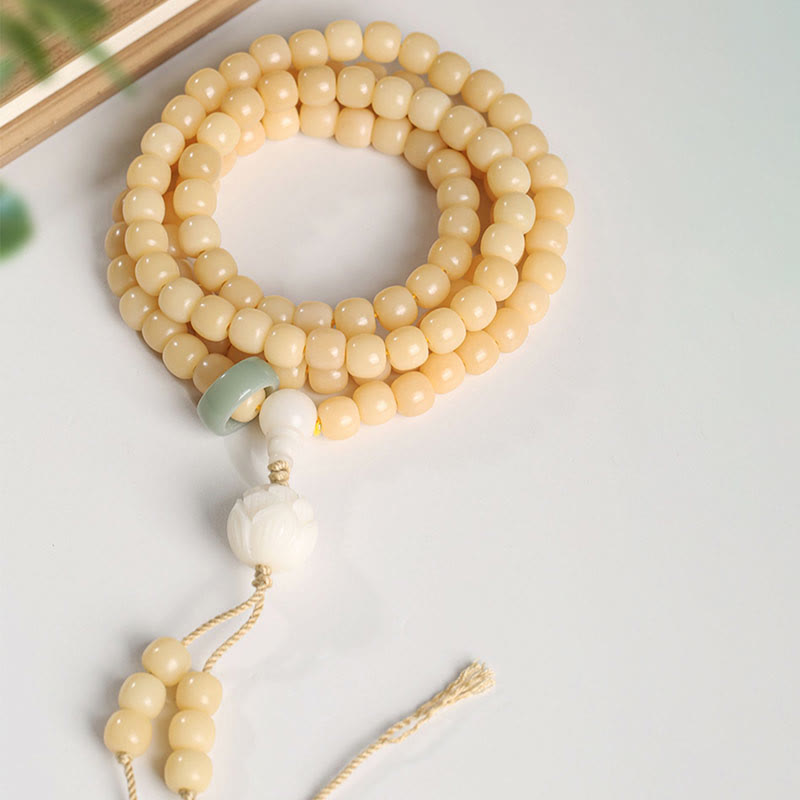 Bodhi Seed Lotus Dzi Bracelet - Triple-coiled bodhi mala on white with wood and leaf accents, lotus pendant