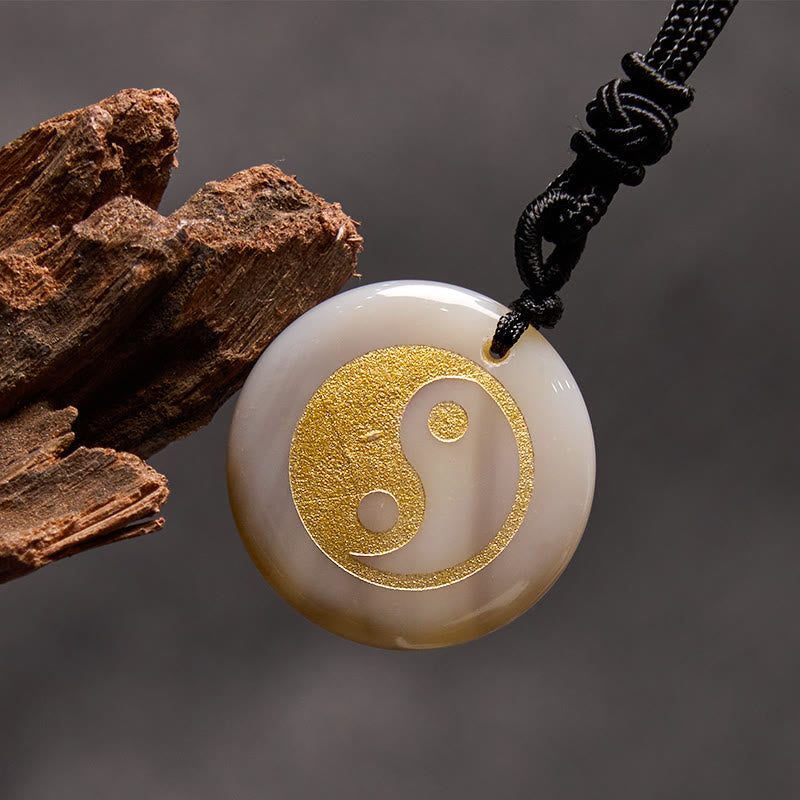 Yin Yang Crystal Necklace – Cream stone disc pendant with gold yin-yang inlay, smooth off-white polished finish on black cord