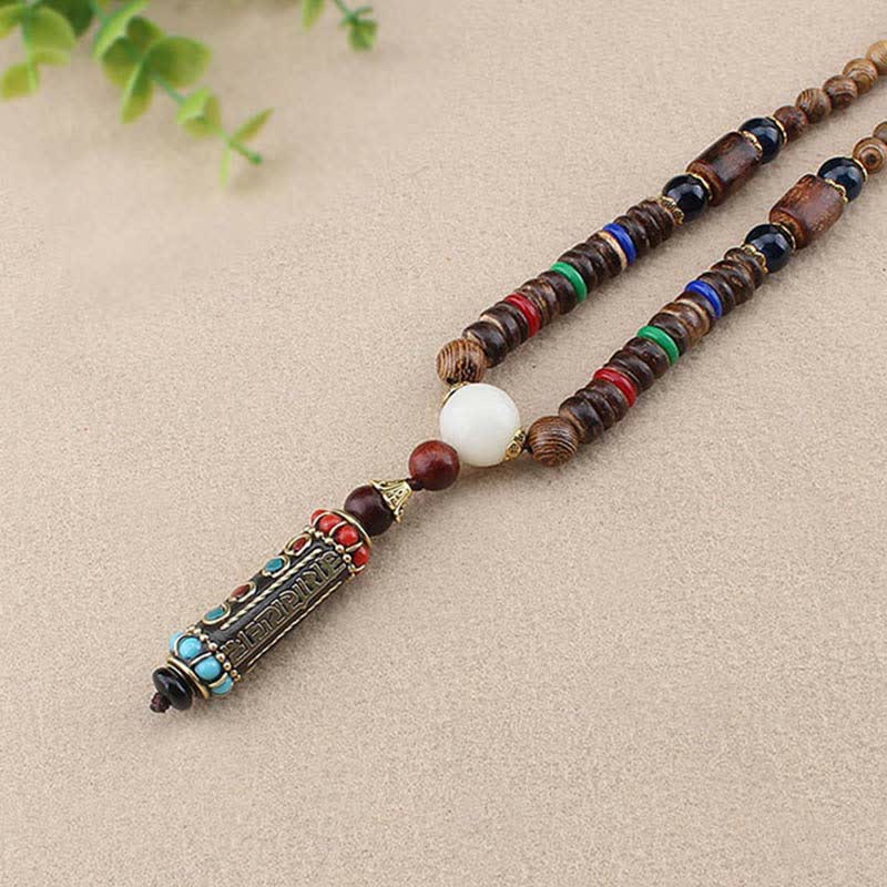 Wenge Wood Dzi Bead Mantra Necklace - Overhead view of striped wood beads with engraved bronze amulet