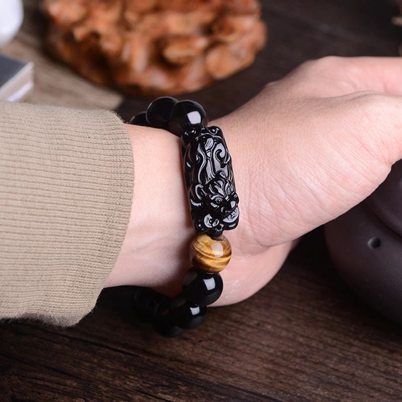 Black Obsidian Tiger Eye PiXiu Bracelet worn on wrist, carved bead detail, traditional Chinese wealth amulet