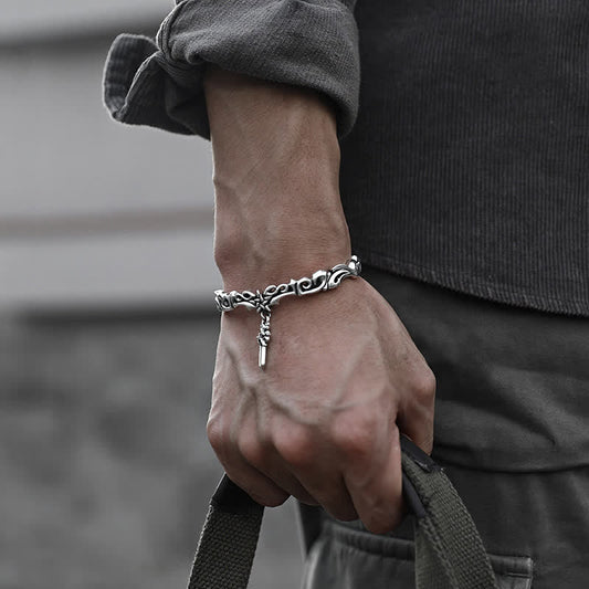 Viking twisted braided copper balance bracelet worn on male wrist with oxidized silver finish scrollwork pattern and cross charm pendant in casual lifestyle setting