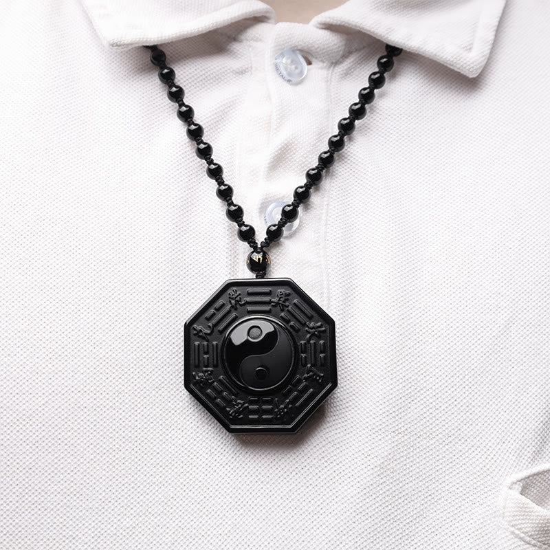 Black Obsidian Yin Yang Pendant Necklace - worn on white polo shirt, obsidian bagua pendant on chest wearable shot