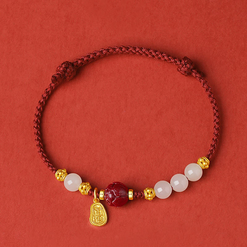 24K Gold Jade Cinnabar Lotus Bracelet – Deep red woven cord with gold floral spacers, white jade beads and cinnabar focal, top-down flat lay