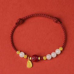 24K Gold Jade Cinnabar Lotus Bracelet – Deep red woven cord with gold floral spacers, white jade beads and cinnabar focal, top-down flat lay