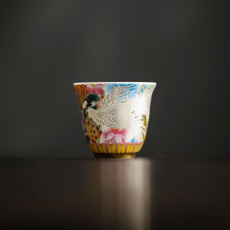Dragon Phoenix Ceramic Teacup - Frontal view of white phoenix with pink blooms on dark surface, Fine porcelain