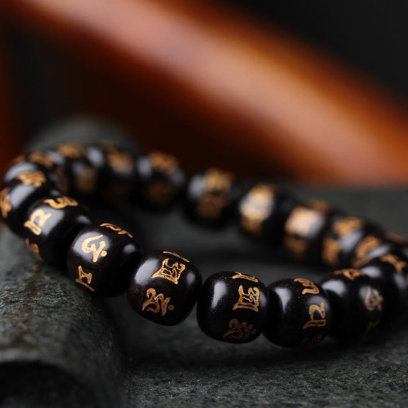 Ebony Wood Om Mani Padme Hum Bracelet – Extreme macro of gold-inscribed beads on stone, spiritual jewelry