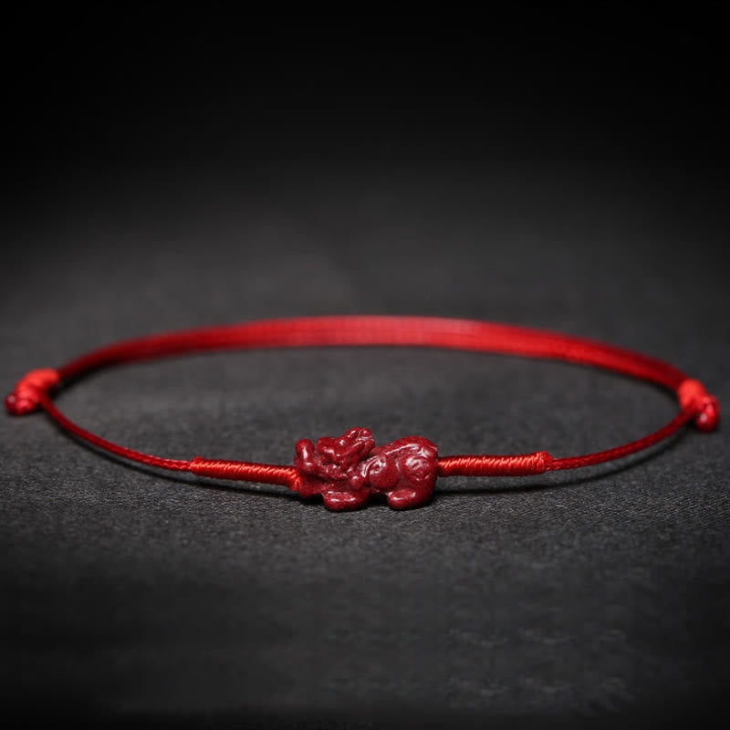 Cinnabar PiXiu Lotus Koi Fish Blessing Braid Bracelet – close-up of PiXiu carving on red cord against dark background, detailed handmade craft