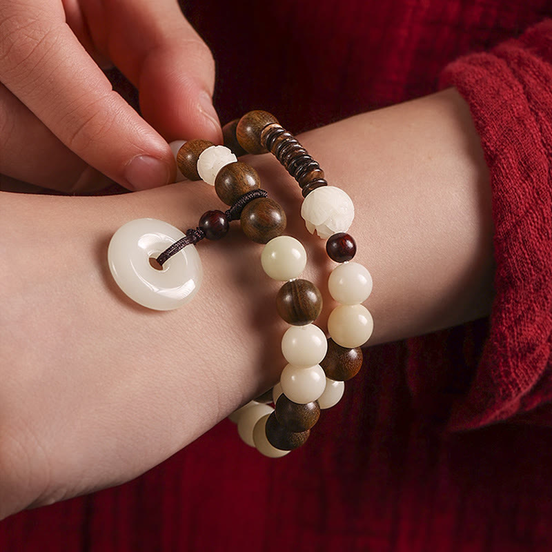 Bodhi Seed Sandalwood Lotus Bracelet - wrist presentation on burgundy fabric, carved lotus focal bead
