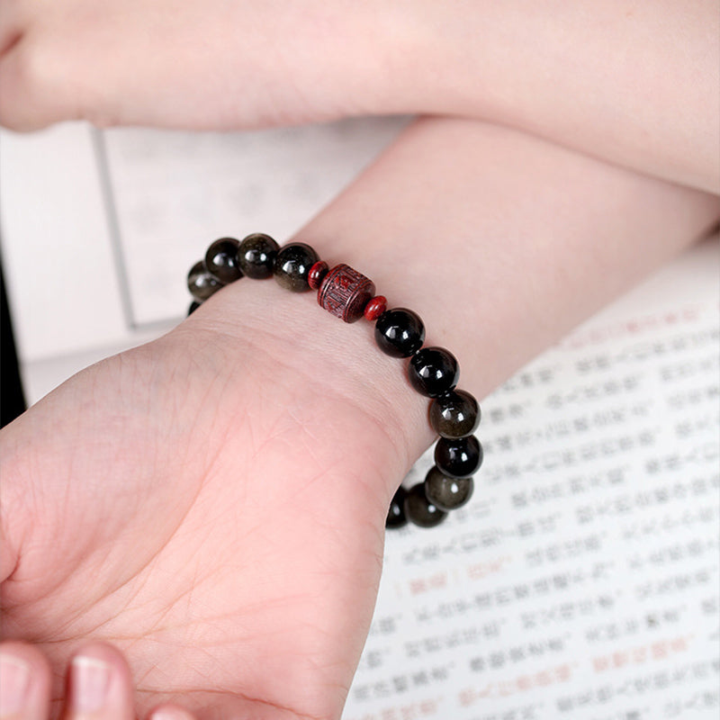 Gold Sheen & Rainbow Obsidian Fu Bracelet – worn on wrist with open book, Chinese cultural jewelry