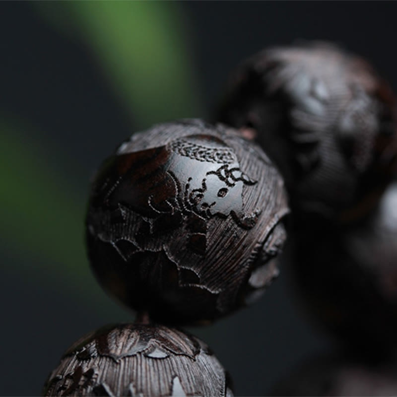 Ebony Wood Yin Yang Gourd Balance Bracelet - close-up of lucky boy figure carving on dark wood bead, artisan carved bead detail