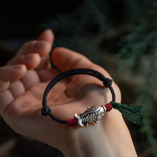 925 Sterling Silver Koi Fish Bracelet – koi charm bracelet on palm in outdoor setting, red wraps and green tassel