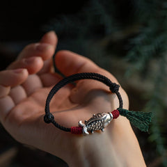 925 Sterling Silver Koi Fish Bracelet – koi charm bracelet on palm in outdoor setting, red wraps and green tassel