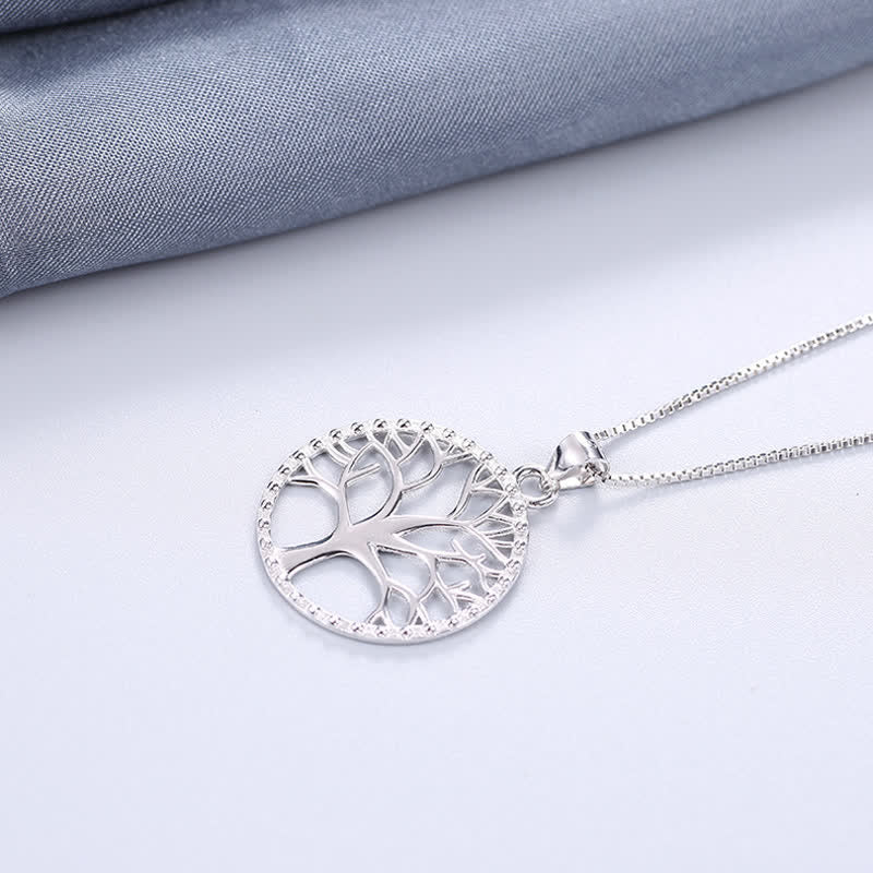 Tree of Life Sterling Silver Necklace – pendant on white with blue-gray fabric accent, three-quarter view, silver jewelry