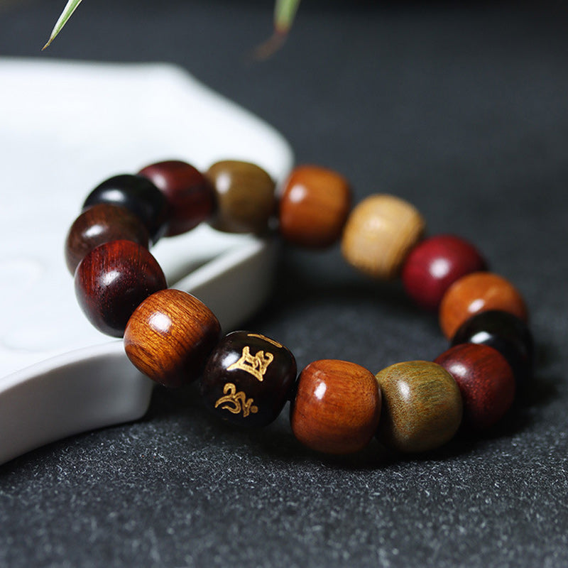 Tibetan Wood Bracelet – mixed wood tones with gold Sanskrit mantra bead on dark stone, prayer bead bracelet