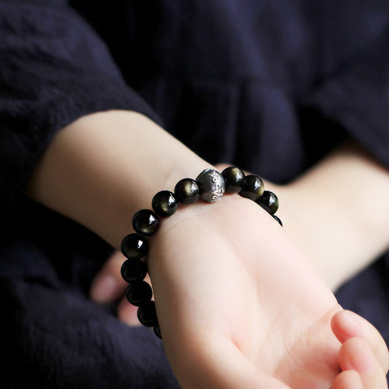 Zodiac Natal Buddha Obsidian Silver Bracelet - Worn on wrist showing golden obsidian sheen and silver charm detail
