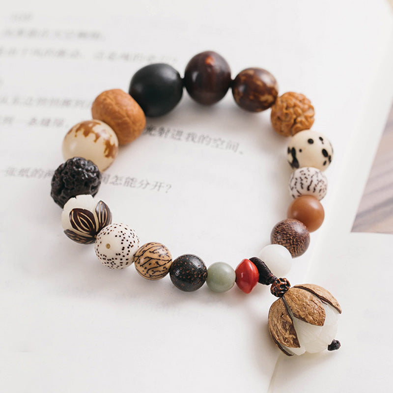 Bodhi Seed Lotus Mala – Elevated view on calligraphy book showing lotus pod pendant, zen accessory