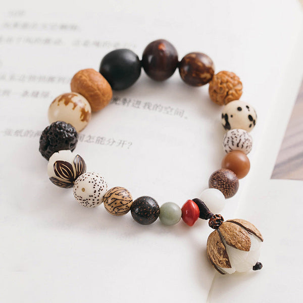 Bodhi Seed Lotus Mala – Elevated view on calligraphy book showing lotus pod pendant, zen accessory